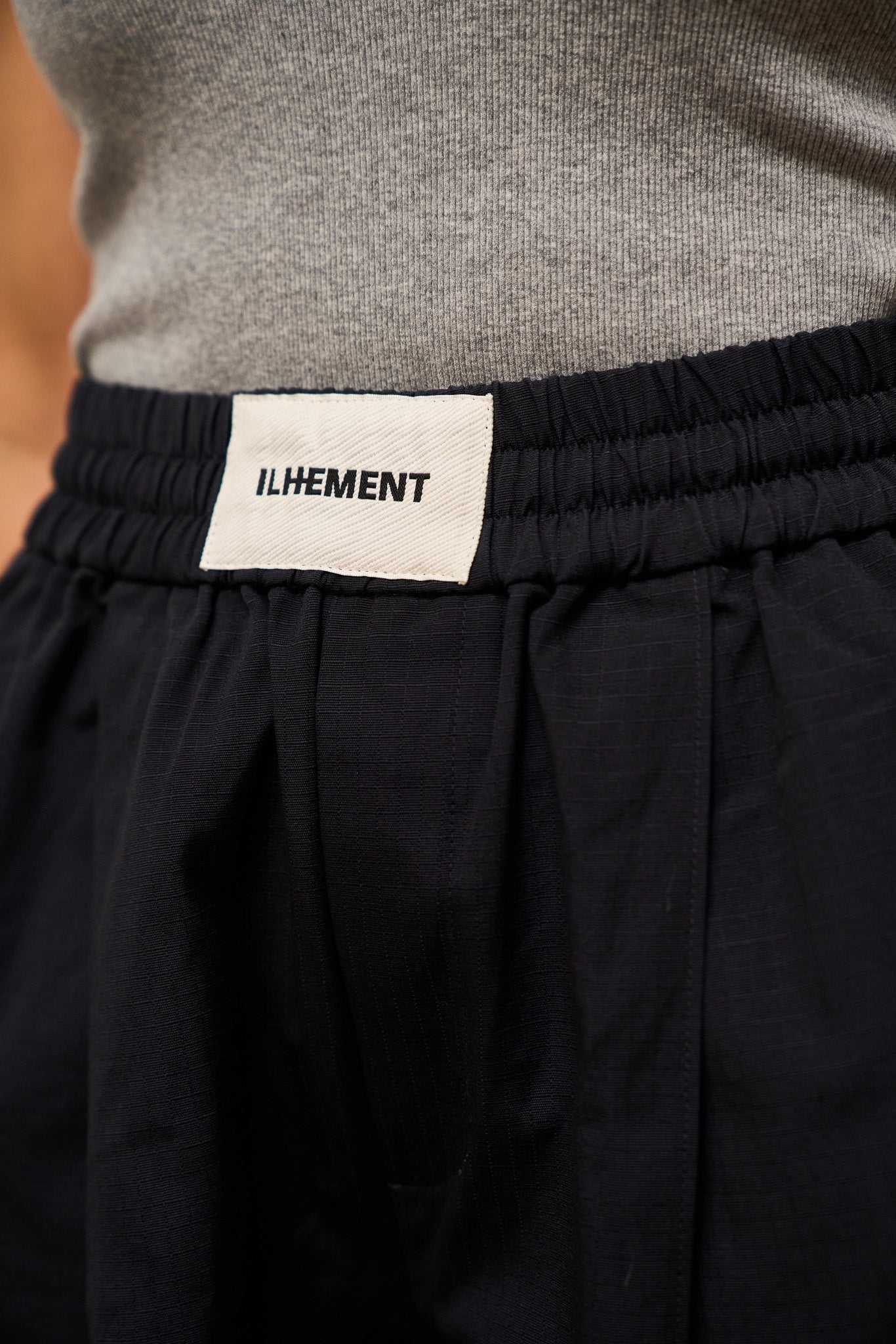 Navy pleated ripstop pants with stitched-down front pleats and oversized silhouette