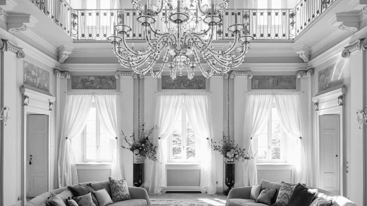 Sunlit salon at Passalacqua on Lake Como with a large Murano glass chandelier and pale classical interiors.