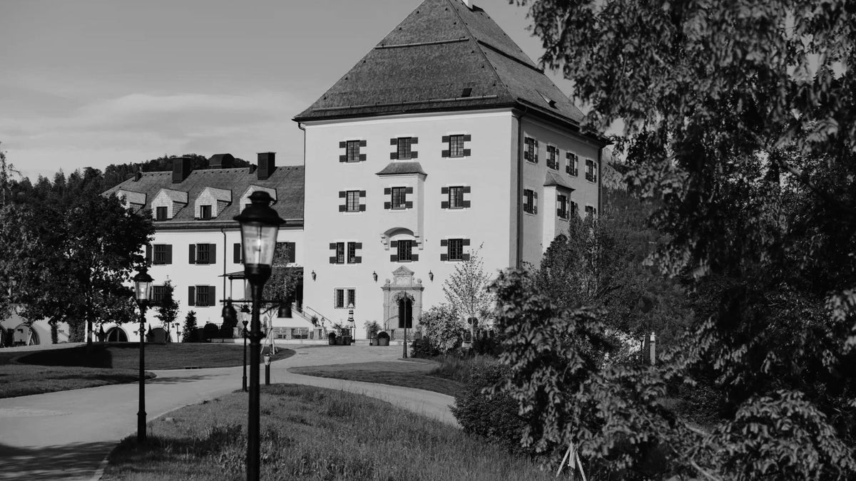 Rosewood Schloss Fuschl castle façade framed by gardens in Austria