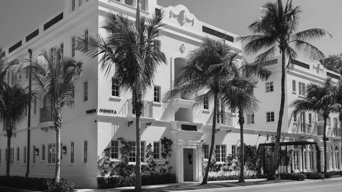 The Vineta Hotel’s Mediterranean Revival façade in Palm Beach, framed by palms and tropical planting.