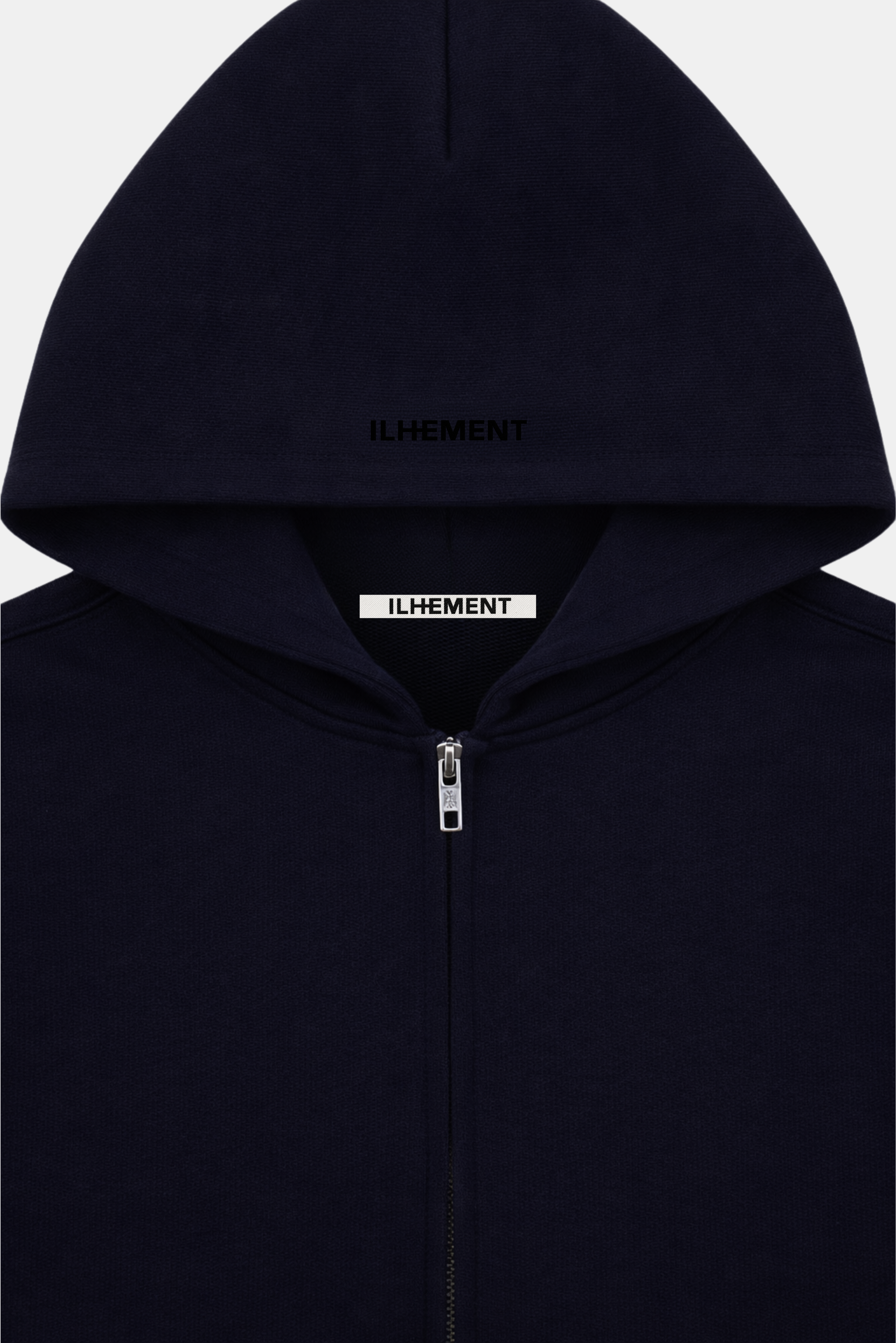 A close-up of a dark navy zip-up hoodie with the brand name 'ILHEMENT' embroidered tonally on the top of the hood and on a white label inside the collar.